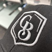 a close up of a black hat with a logo reading 'GB' embroided on it